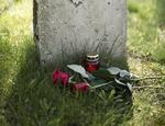Grabstein mit mit zwei roten Rosen und einer roten Kerze