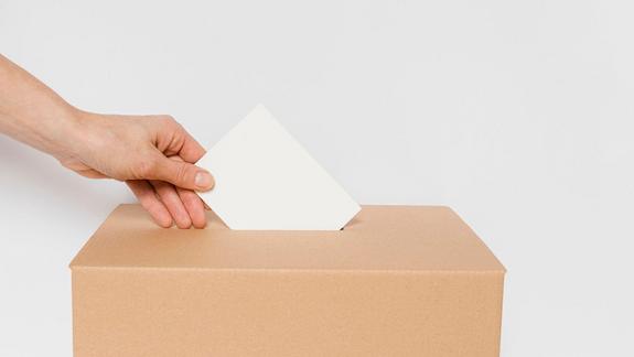Eine Hand mit einem geschlossenem Briefumschlag beim Einwerfen in einer verschlossenen Schachtel
