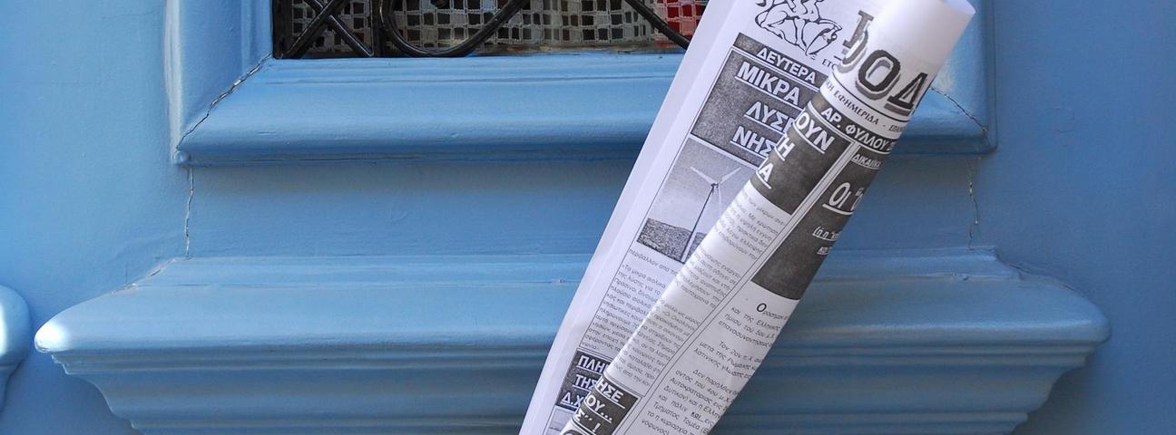 Eingerollte Zeitung im Briefschlitz Blaue Holztüre und eine eingerollte Zeitung im Briefschlitz