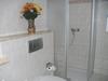 Bildausschnitt vom Bad: Duschkabine aus Glas und die Toilette. Bad besteht komplett aus cremefarbigen Fliesen