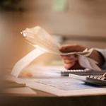 Bild von einer Frau mit einem Taschenrechner und Kugelschreiber in der Hand