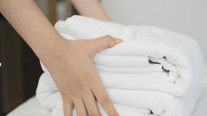 Eine Frau hält ein Stapel gefaltete Handtücher.