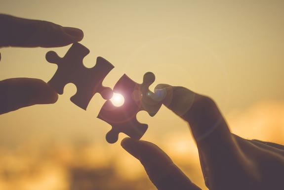 Zwei Puzzleteile , die in der Luft bei Sonnenuntergang zusammengesteckt werden