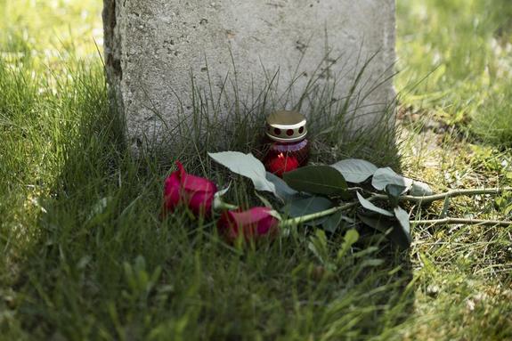 Grabstein mit mit zwei roten Rosen und einer roten Kerze