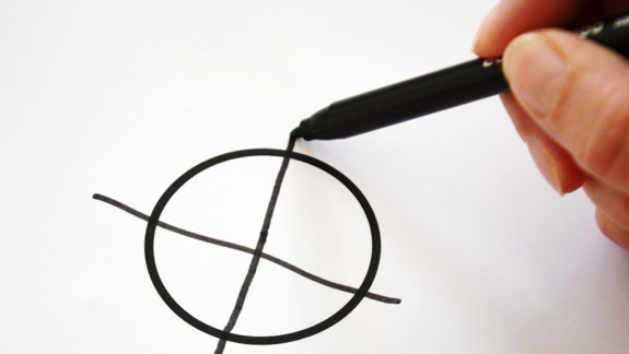 Eine Hand, die in einem Kreis ein kreuz zeichnet. (Symbolbild für Stimmabgabe)