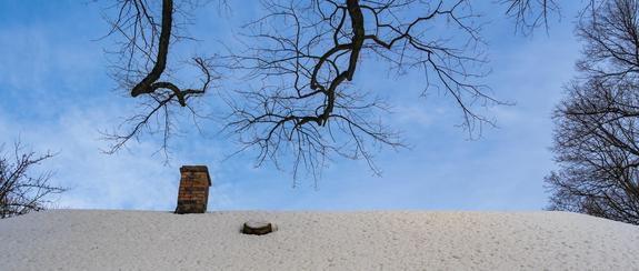 snow-covered roof of an old house with a brick chimney against 