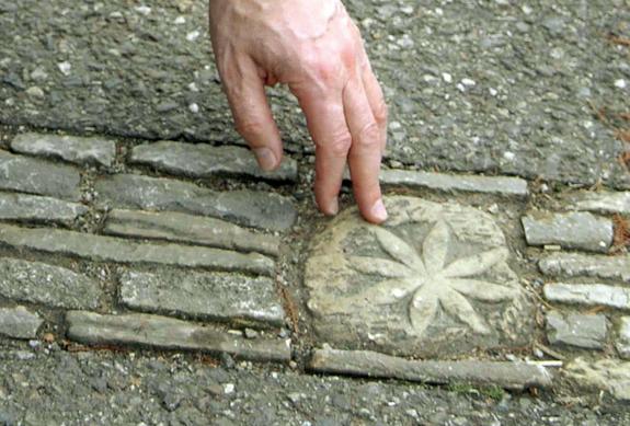 Hand zeigt auf eine Steinstickung mit einem Stern