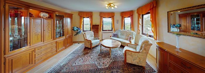 Panoramafoto vom Wohnzimmer. Wohnwand aus Eiche mit orientalischem Teppich in der Mitte und einem Eichenholzsideboard