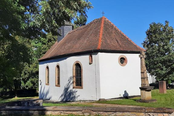 Ein weißes Gebäude (Kapelle) mit einem roten Dach im Sonnenschein