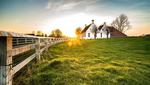 Beautiful shot of a fence leading to a house in a green grass area Bauernhof im Sonnenschein