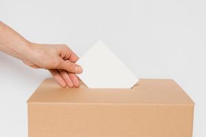 Eine Hand mit einem geschlossenem Briefumschlag beim Einwerfen in einer verschlossenen Schachtel