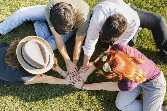 Freunde, die sich die Hände auf der Wiese halten