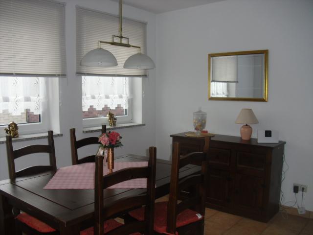 Bild vom Wohnzimmer: Dunkelbrauer Holzesstisch mit passenden vier Holzstühlen. An der Wand steht ein kleiner, dunkelbrauner Holzschrank